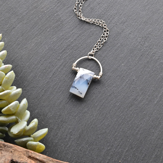 Silver necklace with a pendant on a dark surface